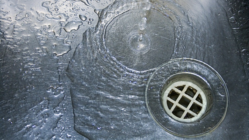 Vatten som rinner  ner i avloppet på en diskbänk