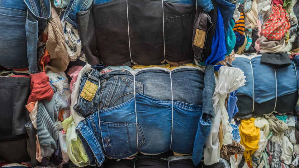 Many piles of clothes, mostly jeans, tied up.